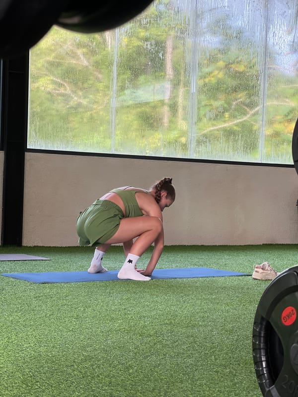 Woman in athletic wear sits on mat indoors