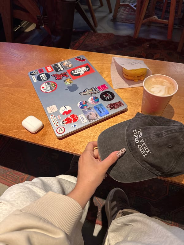 Person with leopard nails holds cap at laptop table