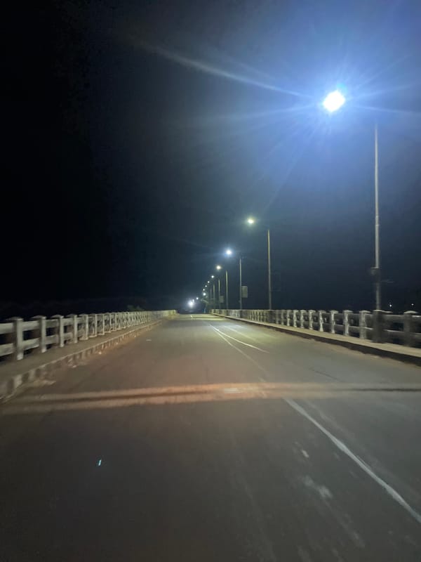 Nighttime streetlights illuminate dark roadway in Paliem, India