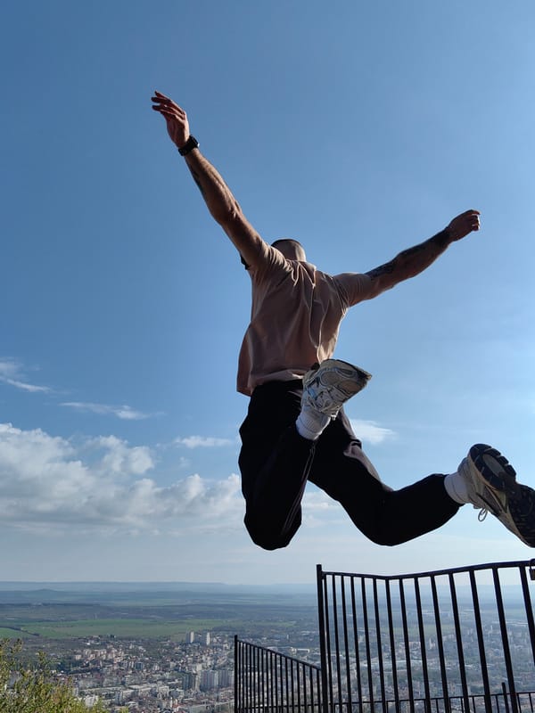 Person celebrates with jump against Shumen cityscape