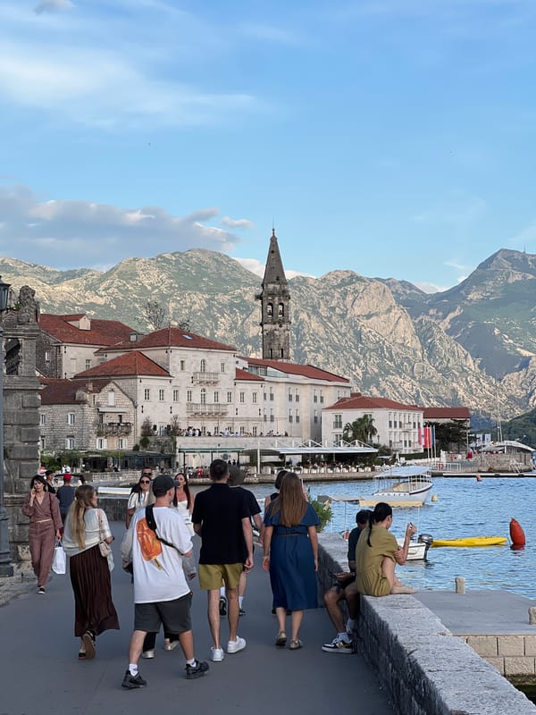 Pedestrians walk waterfront sidewalk in Perast, Montenegro