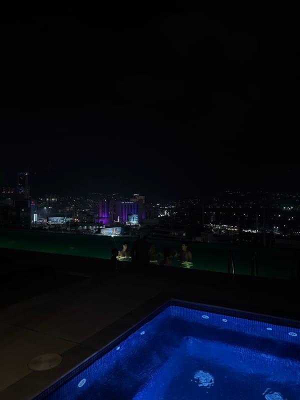 Rooftop pool overlooks San Pedro Garza García skyline at night