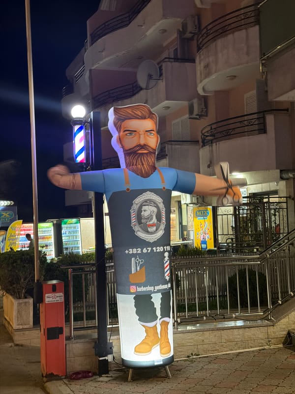 Inflatable barber mascot outside a gentleman's barbershop at night