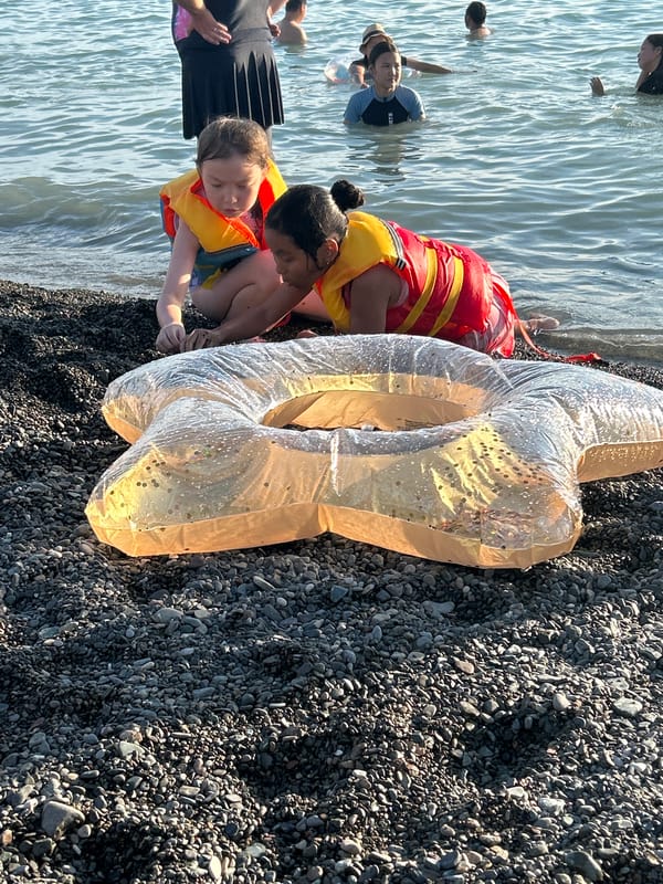 Life vests, pebbles, and a banana boat at the shoreline
