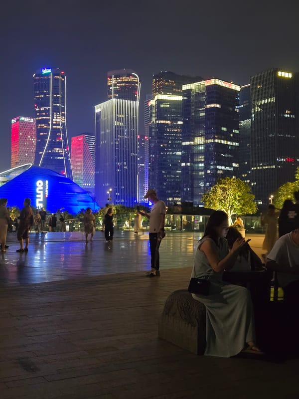 Evening strollers enjoy illuminated Hangzhou skyline and waterfront promenade