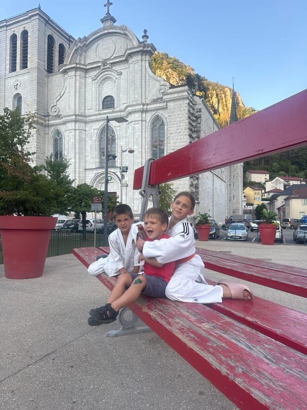 Oversized red bench art installation outside Saint-Claude's historic abbey