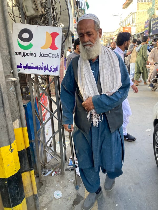 Elderly man walks street in traditional dress, Quetta