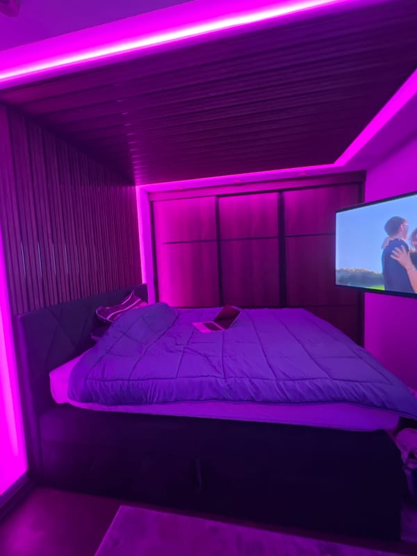 Purple-lit room with TV showing embrace scene in Varna