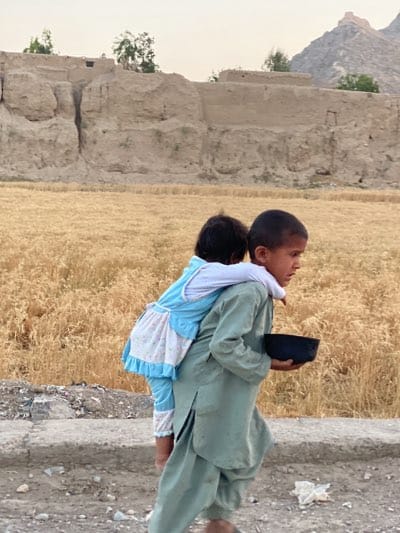 Child carries another on back in Kandahar