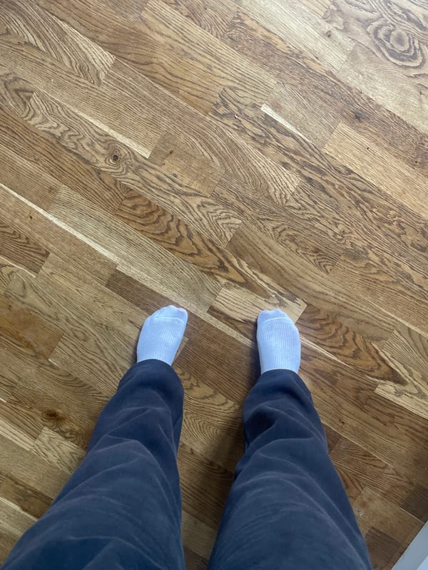 Person in sweatpants and white socks on wooden floor