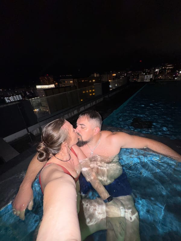 Romantic pool encounter captured at Beppu rooftop overlooking illuminated tower