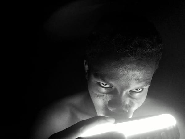 Person illuminates face with bright device in Keffi darkness