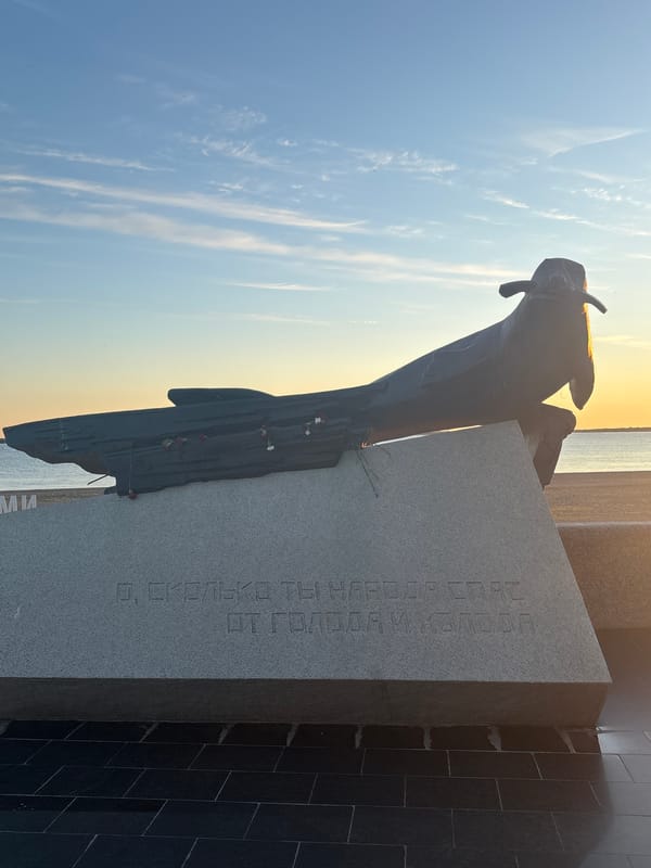 Arkhangelsk waterfront at golden hour: sculptures, coast, and sky