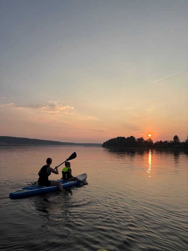 Sunset paddleboarding on calm Russian waters, summer evening