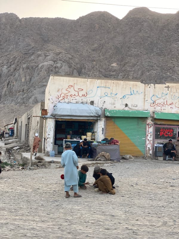 Unpaved street scene amid Kandahar's rugged mountain backdrop