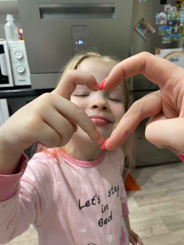 Child in pink pajamas photographed with heart gesture in Izhevsk