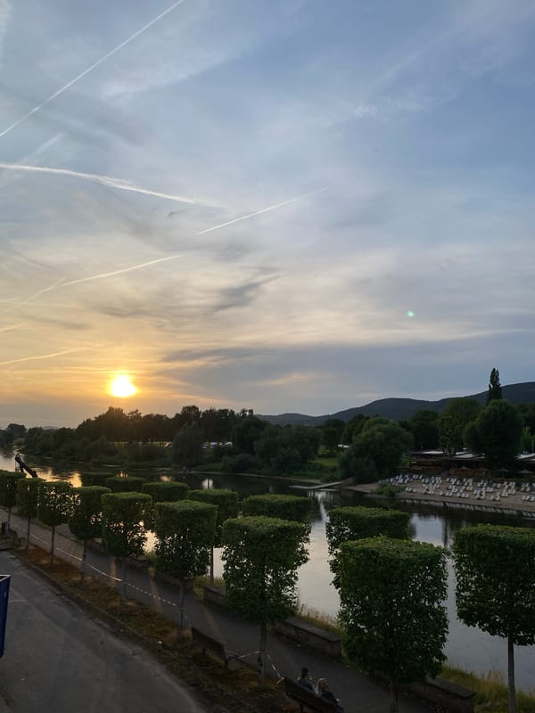 Golden sunset and contrail-filled skies over the Weser River