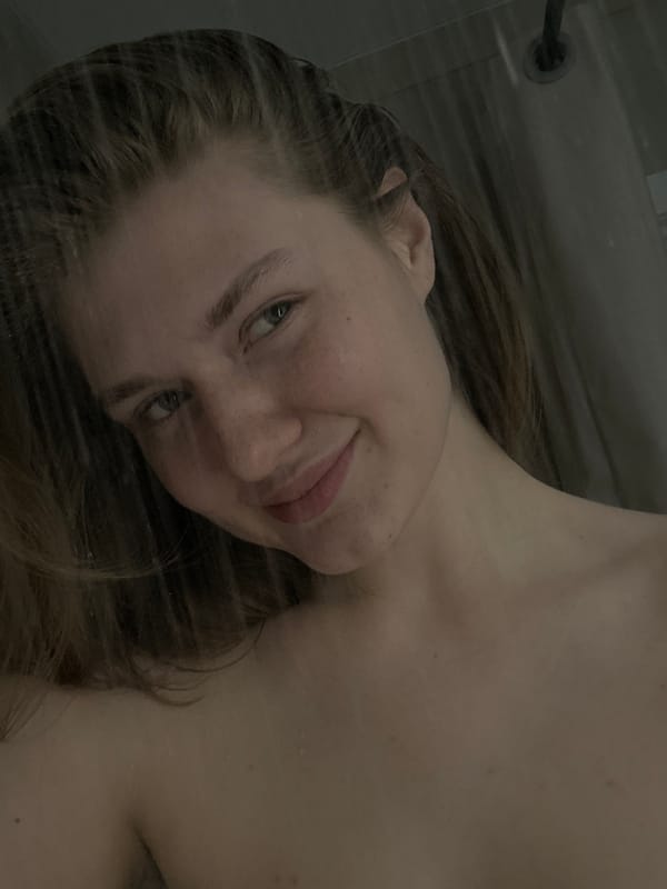 Person photographed in shower setting, water droplets visible