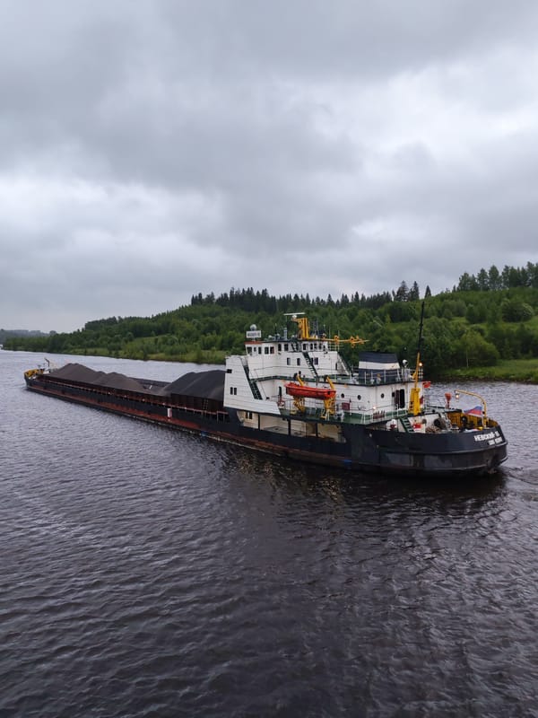 Coal barge navigates a Russian river on an overcast morning