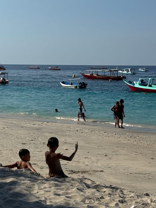 Thatched bar, boats, and turquoise water on an Indonesian beach