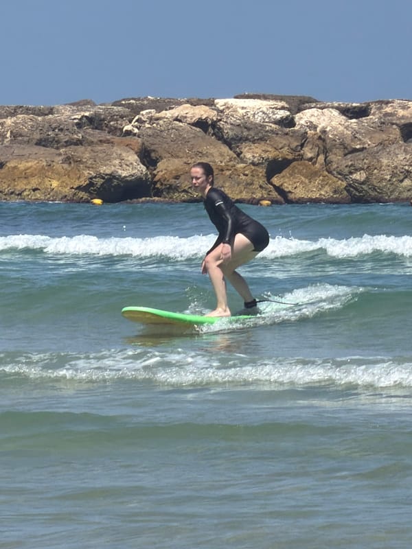 Surfer rides waves near Tel Aviv rocky coastline
