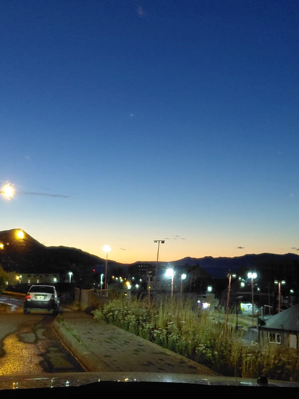 White car parked on wet street during Ushuaia dusk