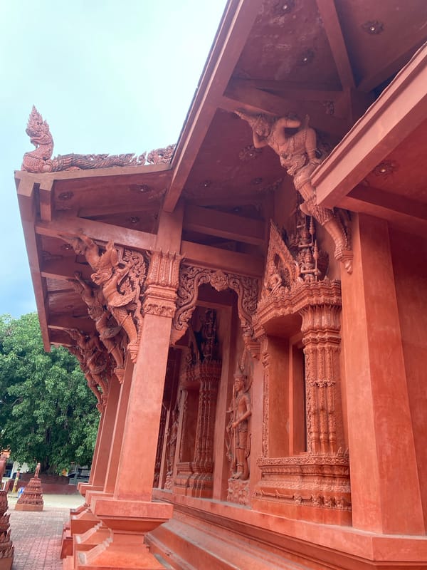 Inside a richly carved red temple complex in Baan Hua Thanon