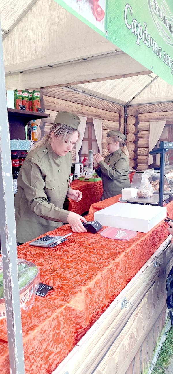 Military-uniformed vendors operate market booth in Rechytsa, Belarus