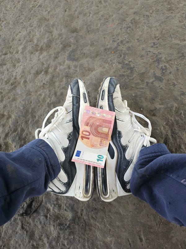 Person places 10 Euro note on shoes in Bulgarian industrial building