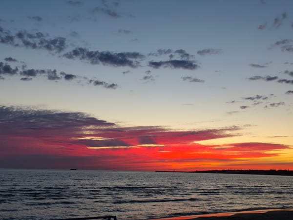 Vivid sunset colors stretch across a calm seascape.