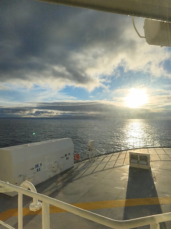 Storm clouds and sun divide the sky over open water