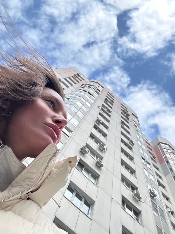 Woman gazes skyward outside building in Krasnogorsk