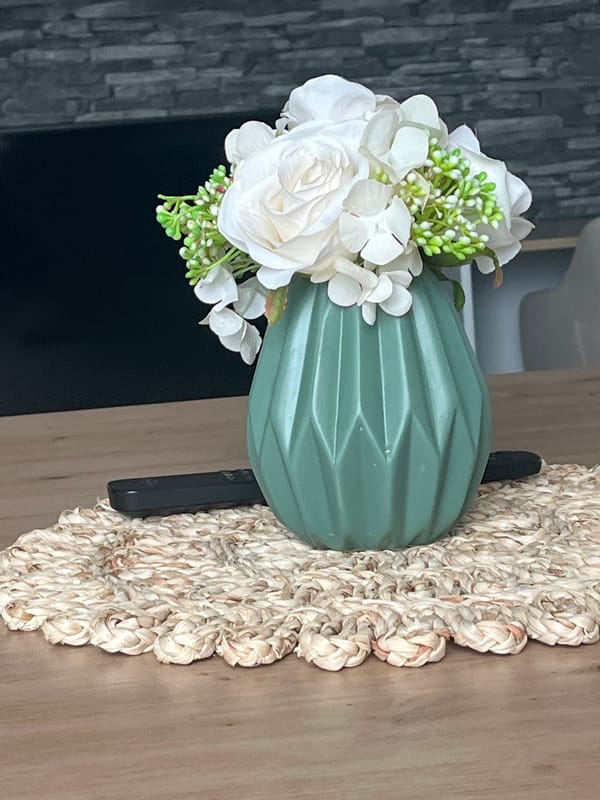 Green geometric vase and white flowers on a wooden table