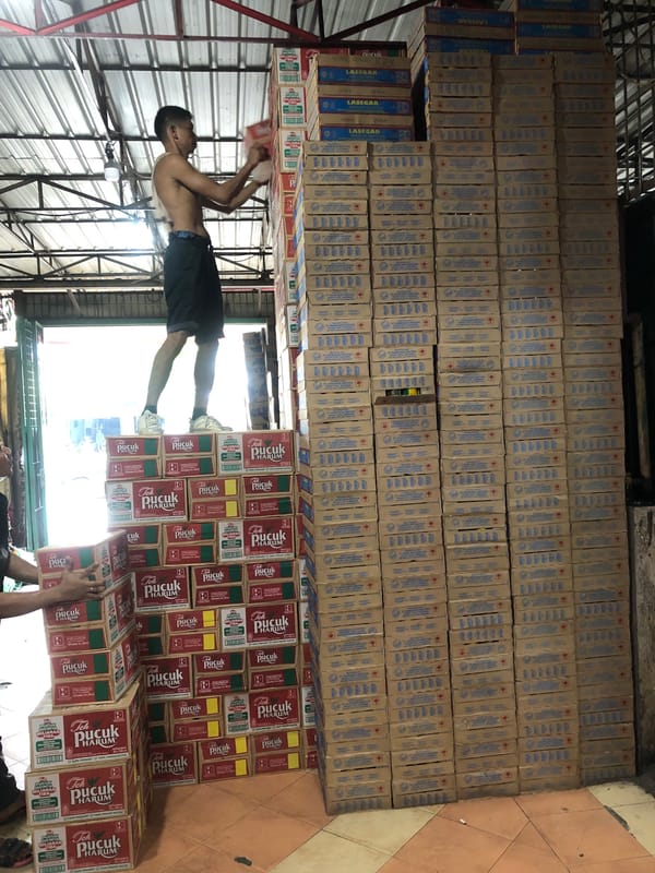 Workers handle beverage inventory in Medan warehouse facility