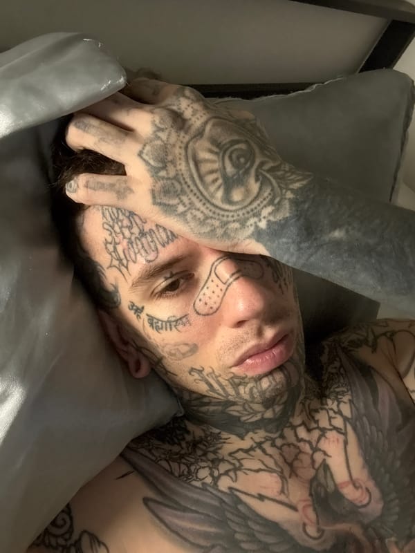 Tattooed person resting on silver pillow in Buenos Aires