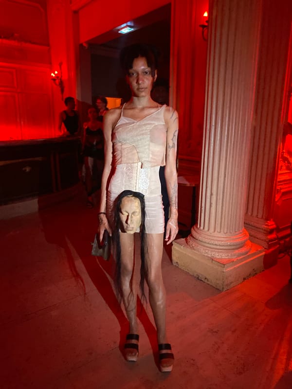 Red-lit Paris event space with mannequin head and white dress tableau