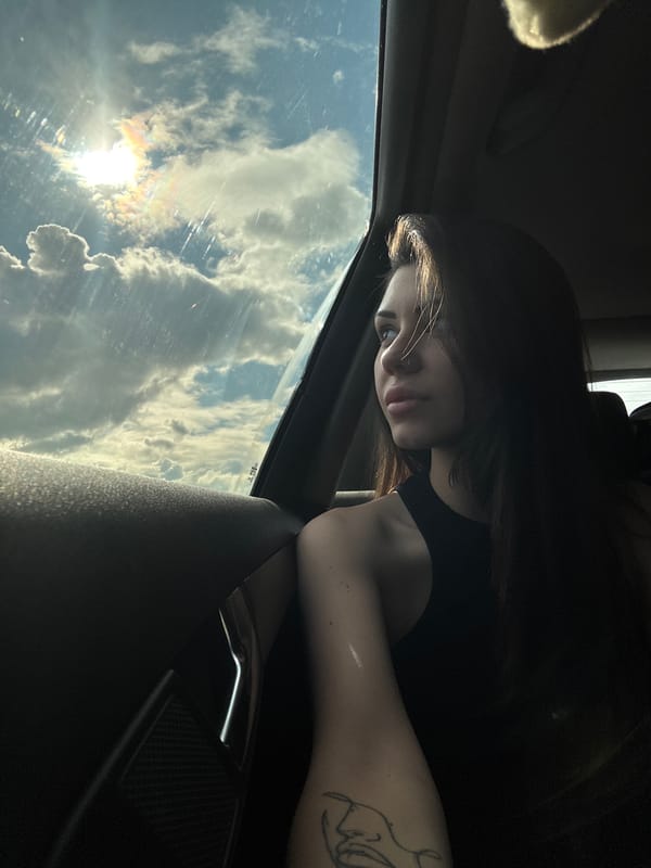 Woman gazes at cloudy sky from car window in Bulgaria