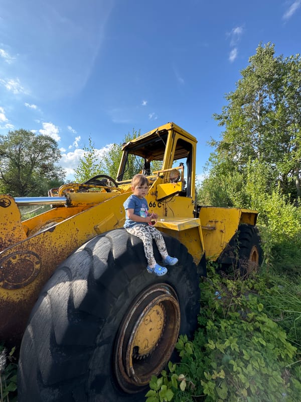 Kid climbs abandoned yellow loader in rural Innolovo, Russia