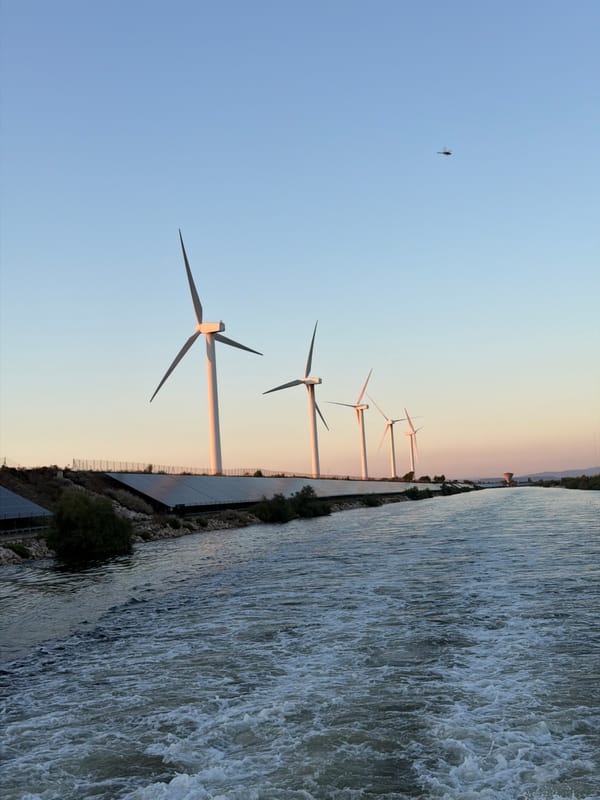 Wind turbines and solar panels line a canal in Arles