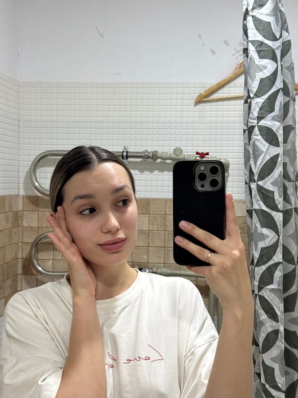 Woman takes bathroom selfie with phone, gold ring visible