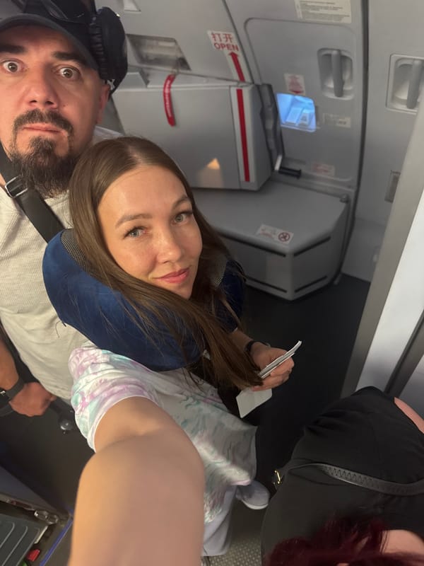 Woman in blue neck pillow photographed on airplane seat