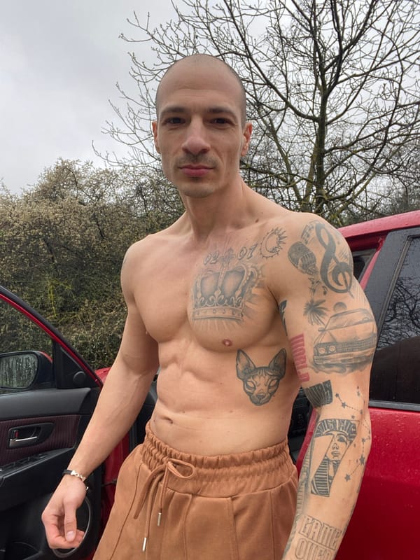 Tattooed man photographed with red car in Pleven