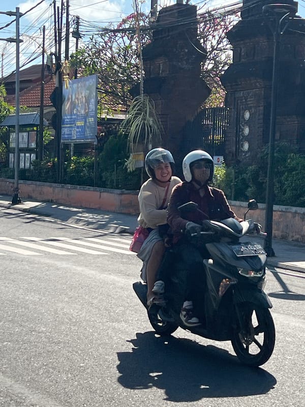 Morning scooter traffic and a stained-glass shopfront in Denpasar