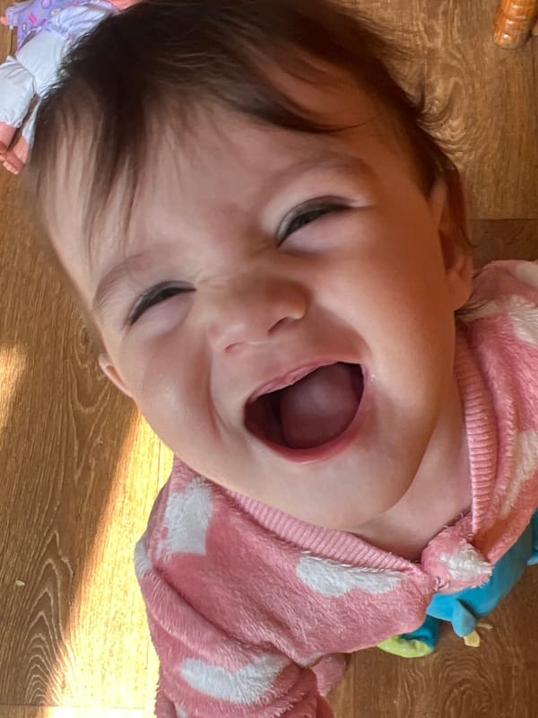 Baby photographed in pink outfit on wooden floor in Elena