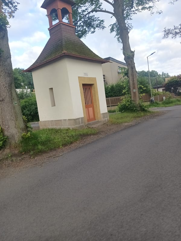 Rural Czech village road with chapel, log house, and local beer banner
