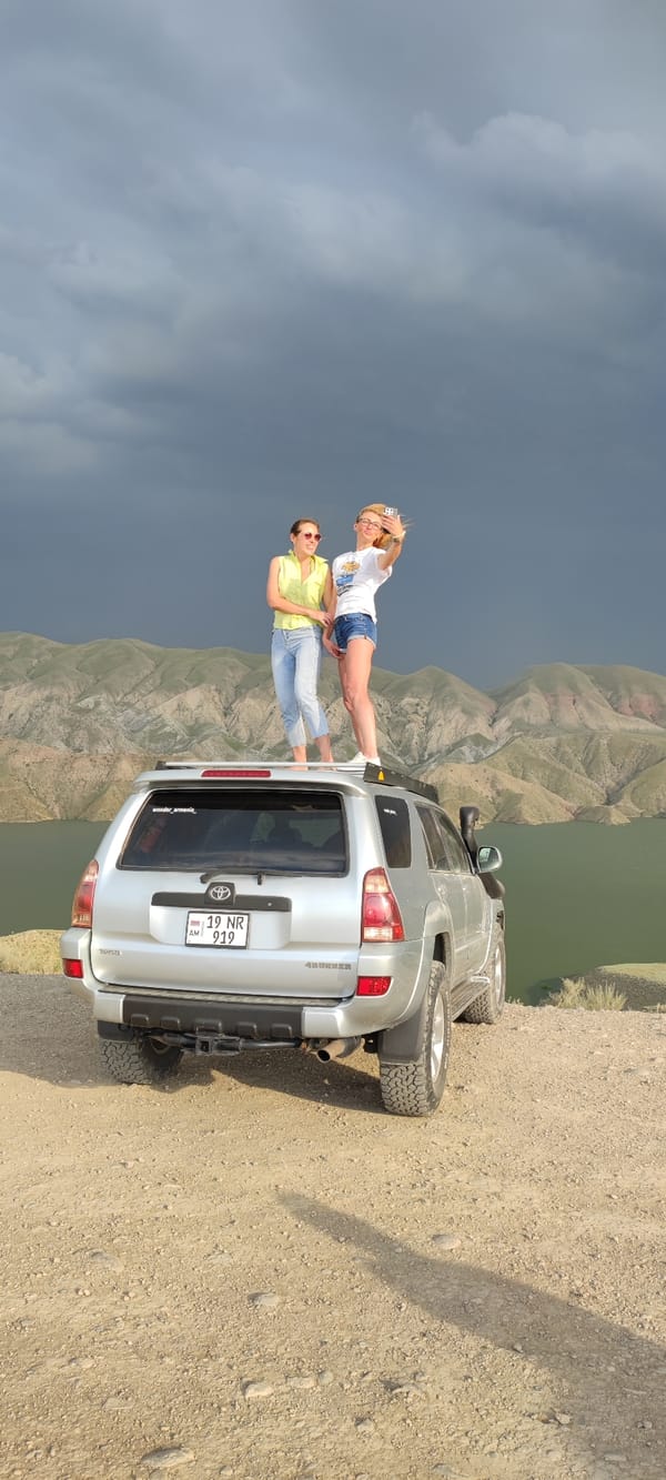 Two women take rooftop selfies on SUV in Armenian mountains