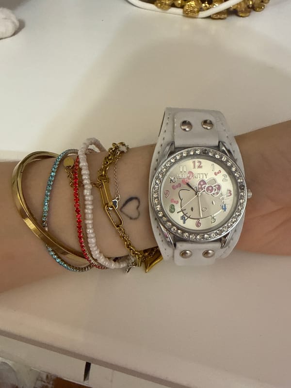 Hello Kitty watch and stacked bracelets, cat in the background