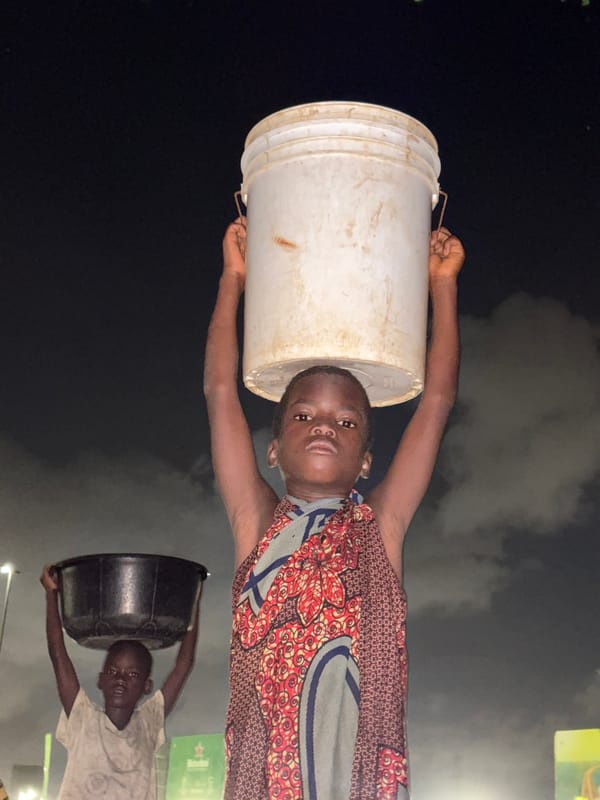 Two people carry buckets on heads in Lagos