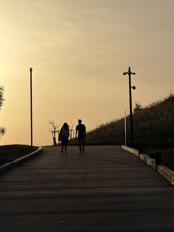 Couple walks Rishon LeZion boardwalk during golden hour