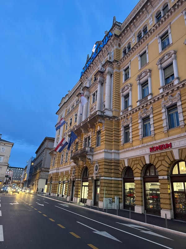Ornate yellow building with Croatian flags photographed in Rijeka